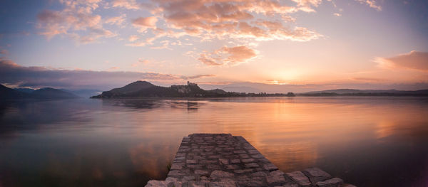 Scenic view of lake maggiore against cloudy sky during sunrise