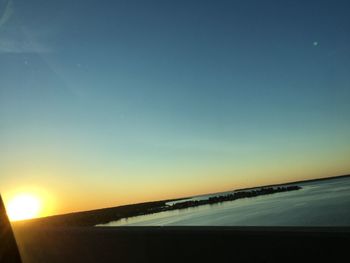 Road by sea against clear sky during sunset