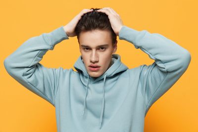 Portrait of young man against yellow wall