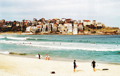 People on beach by sea against sky