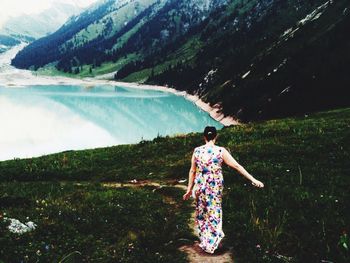 Rear view of woman walking on footpath by lake