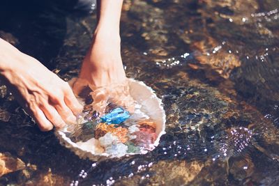 Cropped image of hands picking pebbles from sea