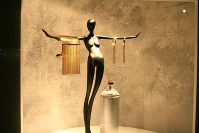 Illuminated statue on table against wall