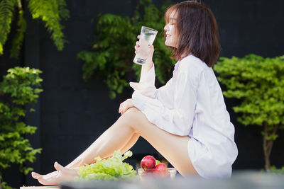 Smiling young woman with food and drink sitting outdoors