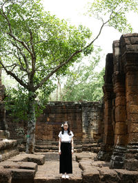 Woman standing on cross against trees