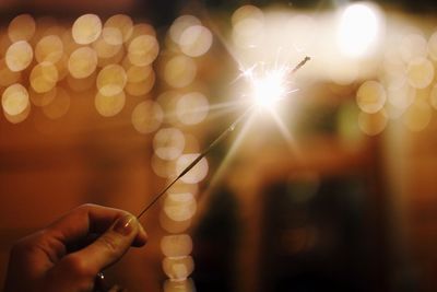 Midsection of person holding sparkler at night
