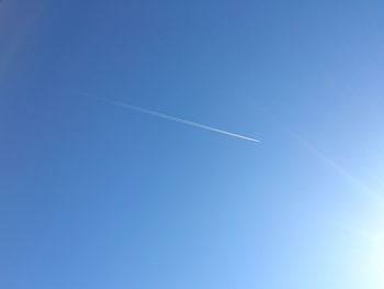 Low angle view of vapor trails in blue sky