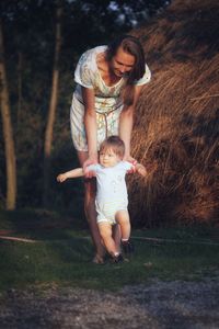 Woman and baby son with blone hair and blue eyes making first steps