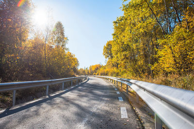 Road amidst trees against sky during autumn