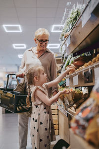 Granddaughter doing shopping with senior woman at grocery store