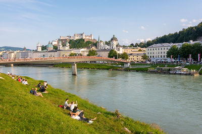 The salzburg skyline with hohensalzburg fortress and people on the bank of salzach river, austria.