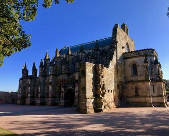 Low angle view of roslin chapel against blue sky