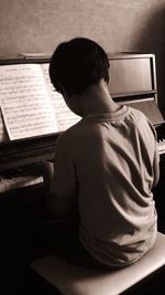 Rear view of man playing piano