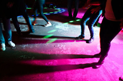 Low section of people walking on illuminated road