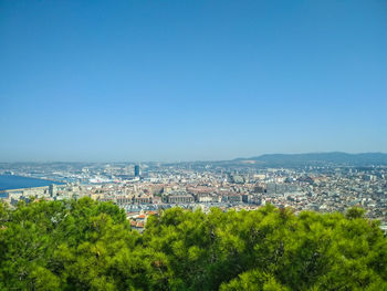 Aerial view of townscape by sea against clear blue sky