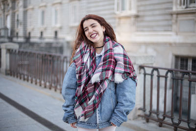 Smiling woman in warm clothes while standing in city during winter