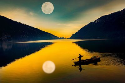 Silhouette man on boat sailing in lake against sky during sunset