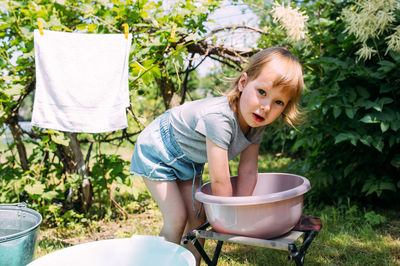 Little preschool girl helps with laundry. child washes clothes in garden