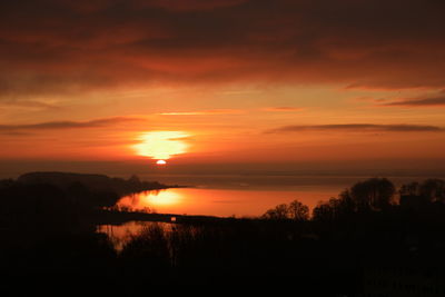 Scenic view of silhouette landscape against orange sky