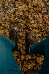 Low section of man standing on autumn leaves