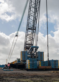 Low angle view of crane at construction site against sky