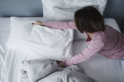 High angle view of girl sitting on bed at home