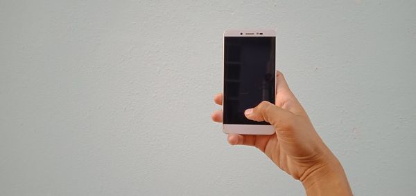 Midsection of person using mobile phone against wall