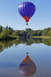 Hot air balloon flying over lake against sky