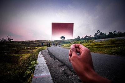 Person hand on road against sky