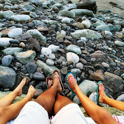 Low section of people standing on pebbles at beach