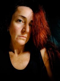 Close-up portrait of young woman against black background