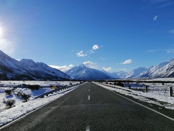 Road amidst snowcapped mountains against sky