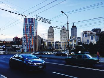 Traffic on city street by buildings against sky