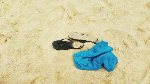 High angle view of towel and slippers on sand at beach