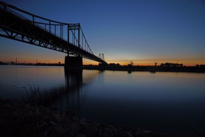 Bridge over river against sky at sunset