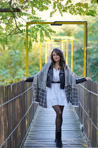 Full length of young woman walking on footbridge