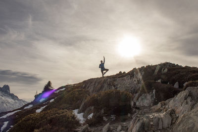 Man skiing on cliff against sky during sunset
