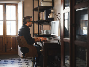 Side view of young man using laptop