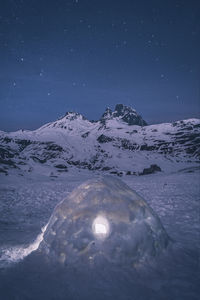 Scenic view of snowcapped mountains against sky at night