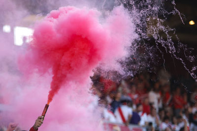 Cropped hand holding distress flare in stadium