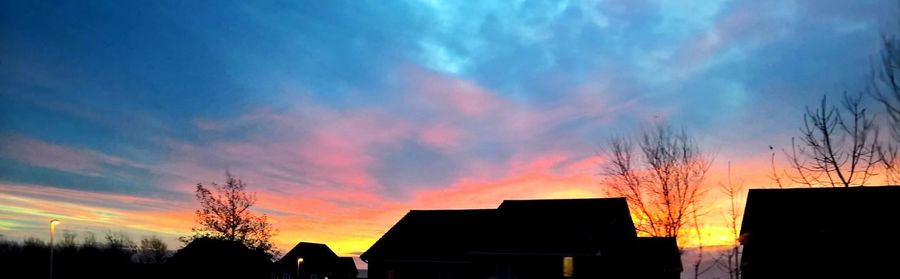 Low angle view of silhouette houses against dramatic sky