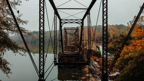 Low angle view of bridge in forest against sky