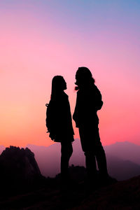 Silhouette woman standing against orange sky during sunset