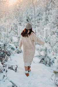 Rear view of woman standing on snow covered land