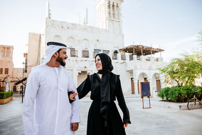 Smiling couple talking while walking on street in town