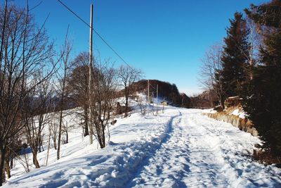 Snow covered landscape against clear blue sky