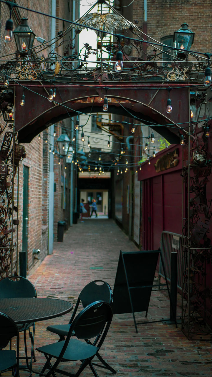 EMPTY CHAIRS AND TABLES AT SIDEWALK CAFE AGAINST BUILDINGS