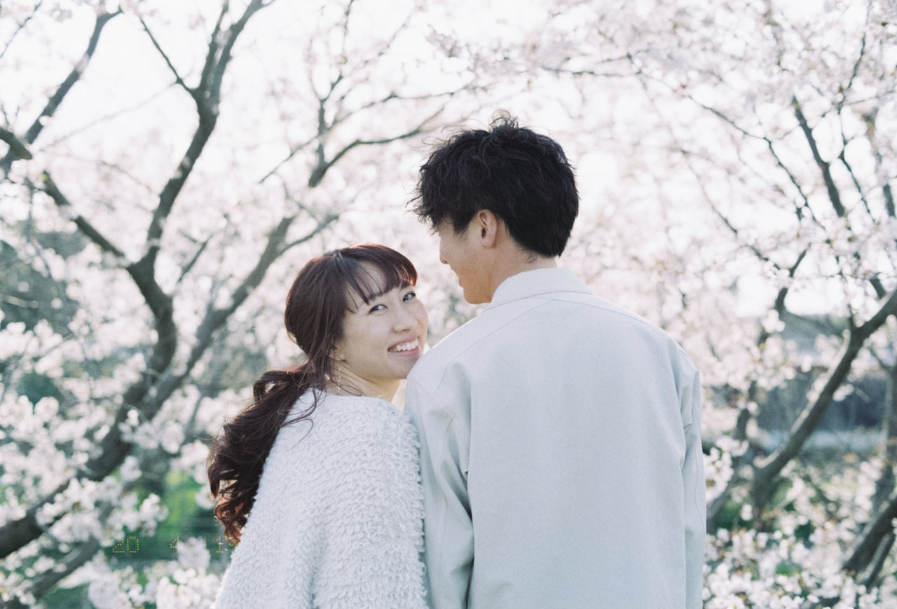 YOUNG COUPLE STANDING ON TREE