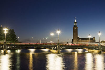 Illuminated vasabron bridge over lilla vartan with stockholm city hall against sky at night