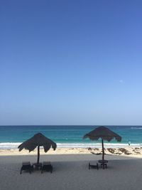 Deck chairs on beach against clear blue sky